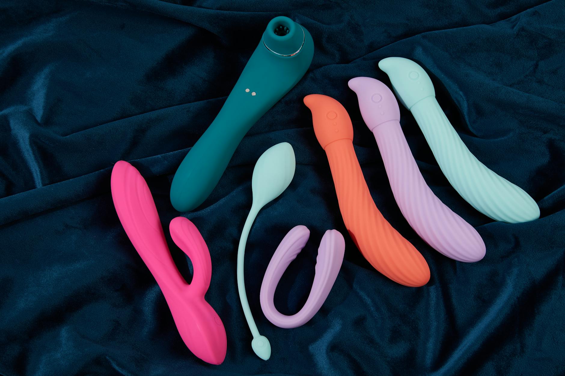 A vibrant collection of various sex toys on a black tray, featuring diverse shapes and colors.