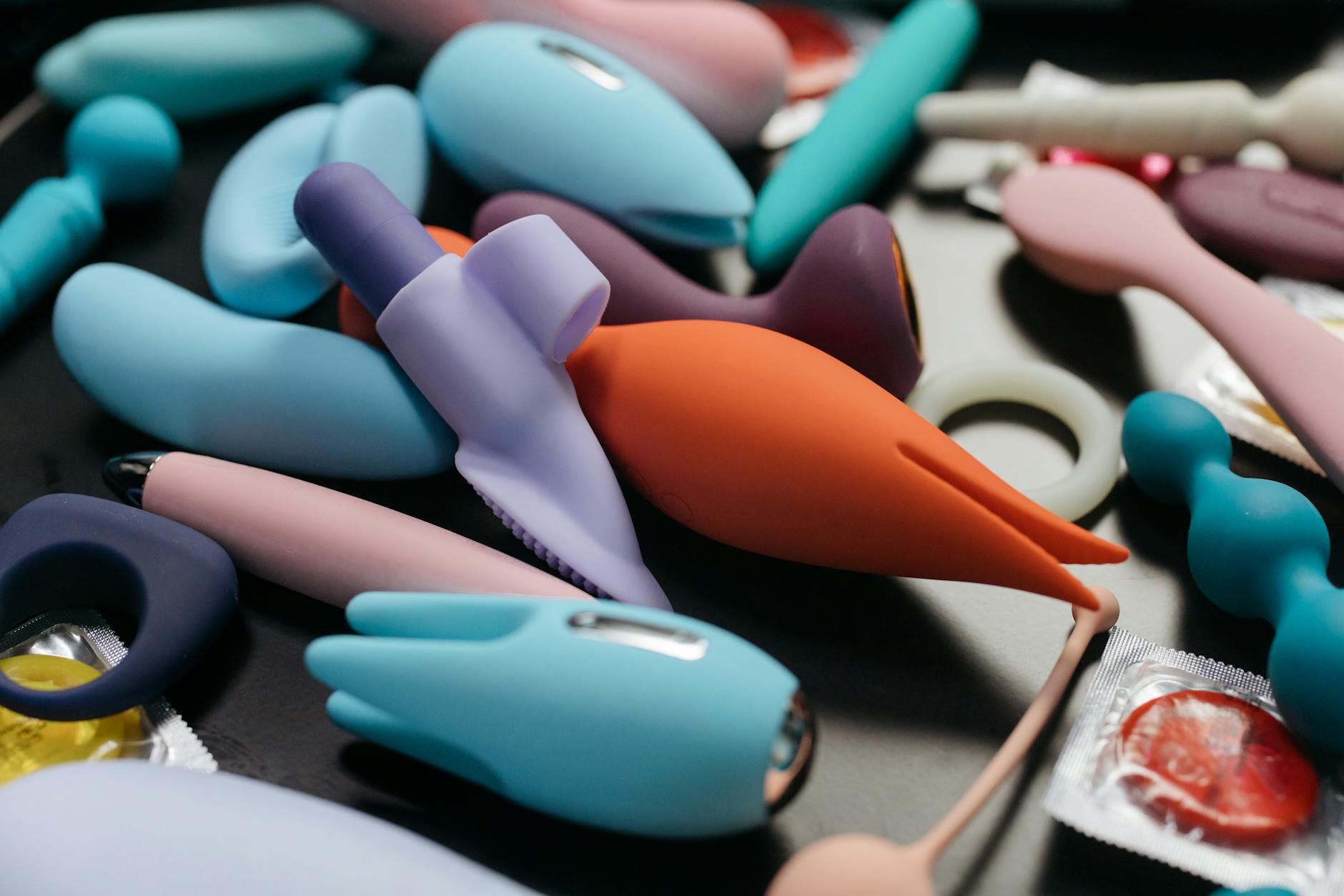 Hands holding a sleek blue vibrator against a soft purple background