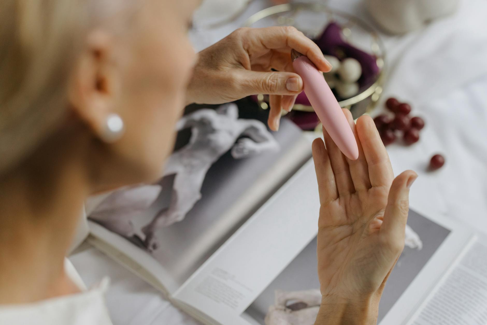 Hand holding a pink vibrator against a purple background, representing intimate wellness during medication adjustment.