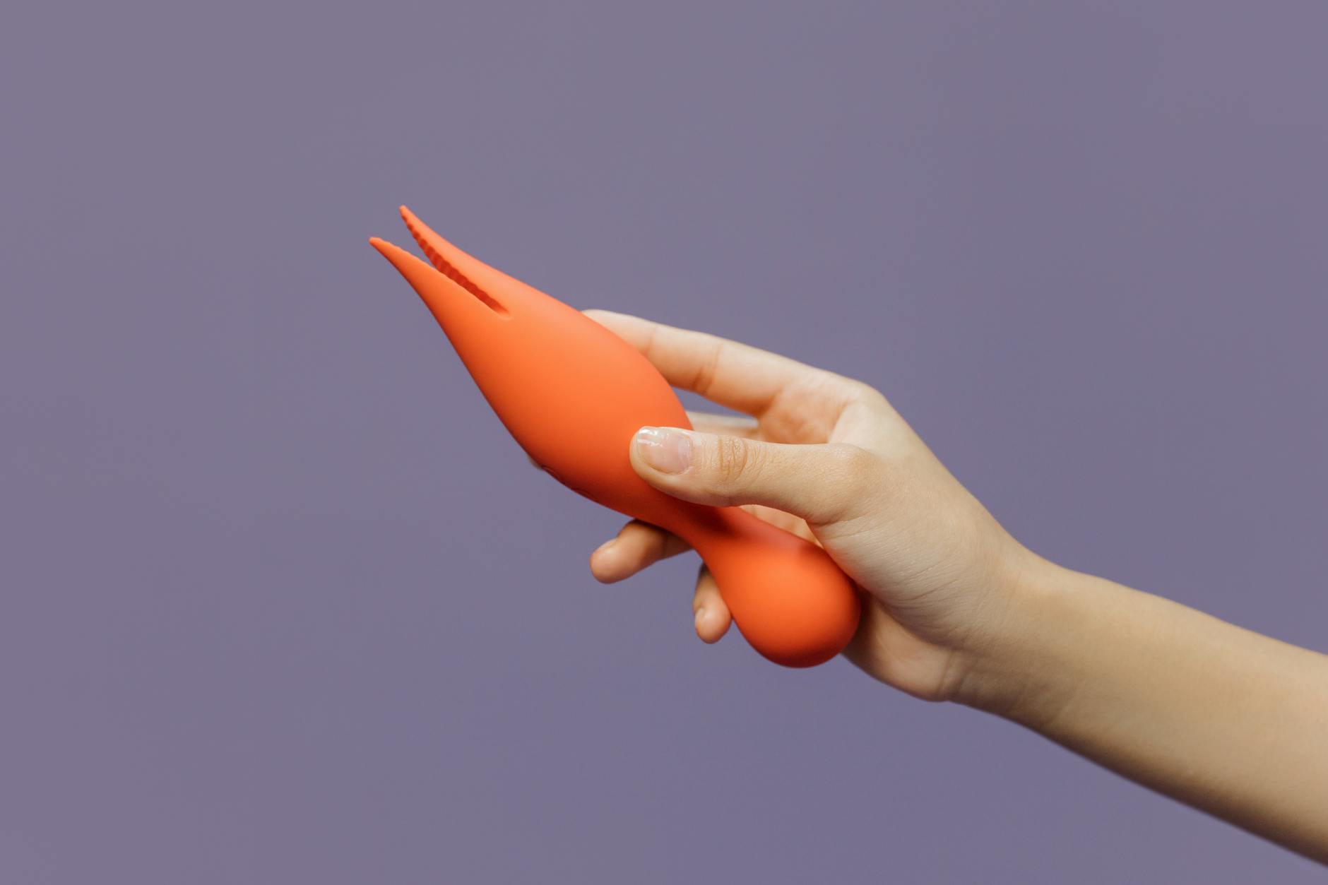 A hand holding a lemon-colored vibrator against a minimalist purple backdrop, representing sensuality and self-care in recovery.