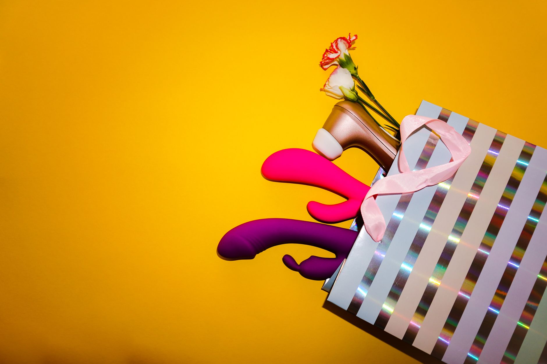 A hand holding a lemon on a soft pink background with additional lemons nearby, symbolizing fresh and natural sensuality.