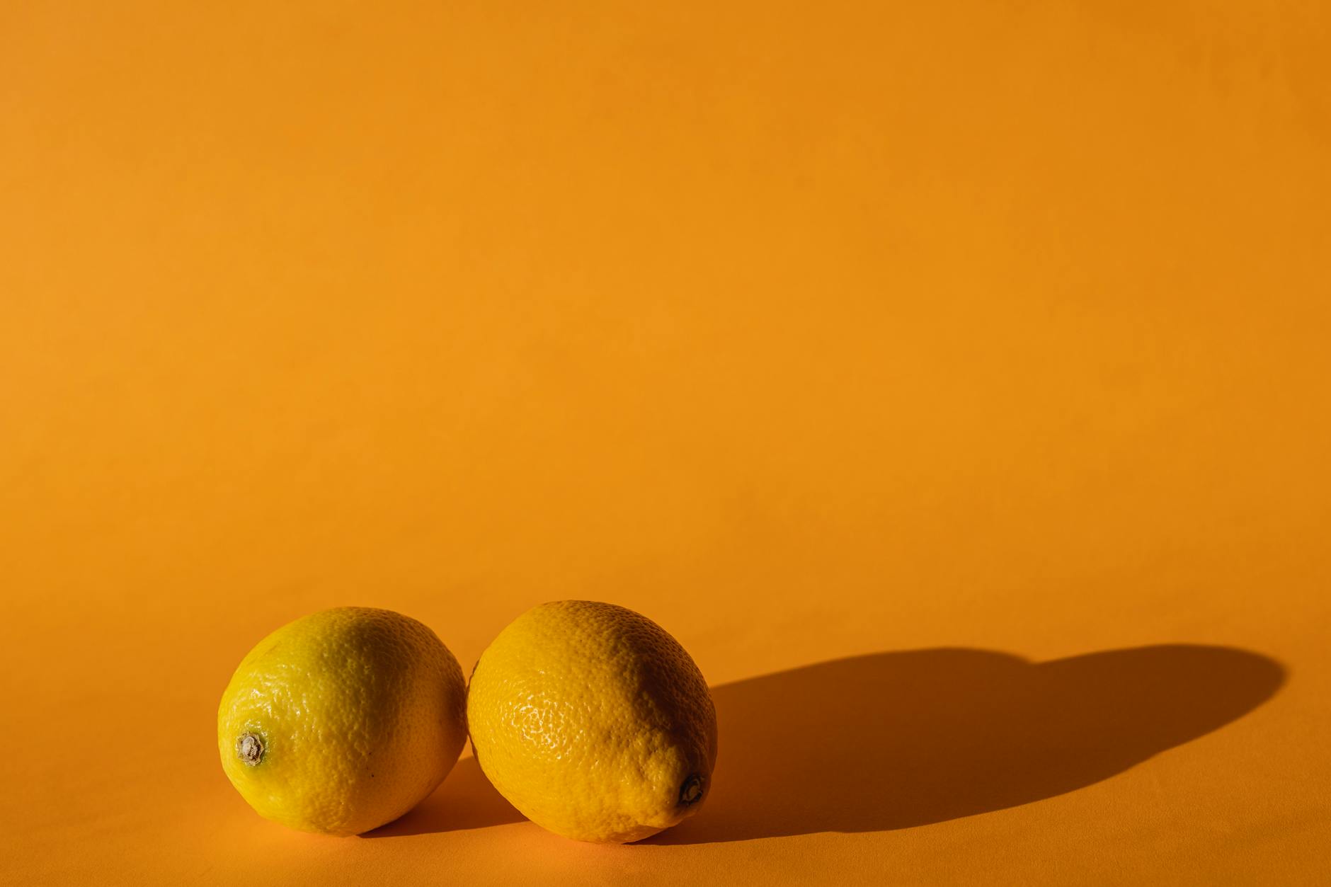 Blue vibrator surrounded by flowers and citrus on a bright yellow background